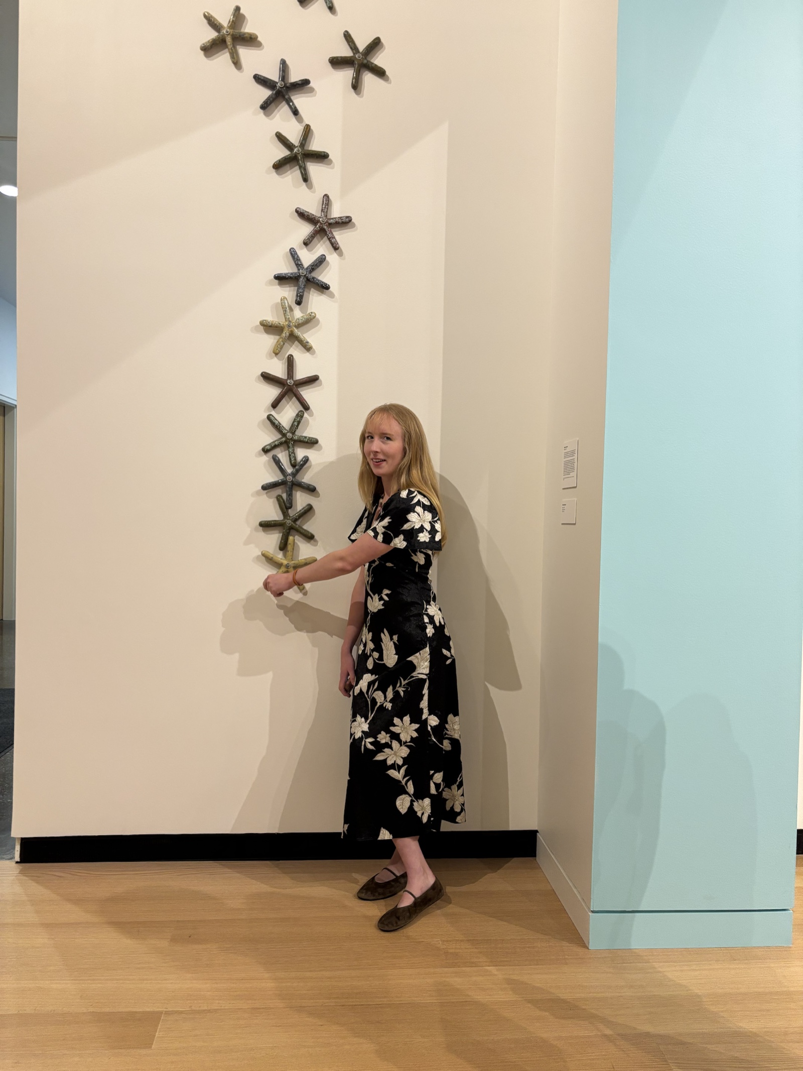 Ellana Glassner beside a wall-mounted ceramic installation
